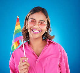 Image showing Woman, lgbtq and rainbow flag in studio portrait, sunglasses and sign for pride with human rights by blue background. Gen z girl, young lesbian student and happy with solidarity, freedom or inclusion