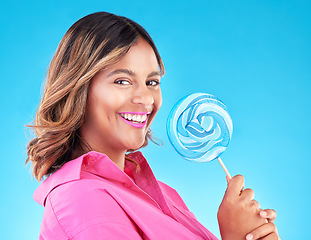 Image showing Woman, lollipop and smile in studio portrait with eating, sweets and excited for food by blue background. Girl, student or young fashion model with candy, beauty or happy with sugar for dessert snack