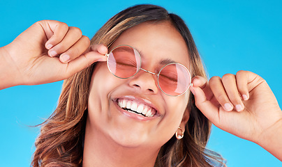 Image showing Fashion sunglasses, face and happy woman in studio isolated on a blue background. Smile, glasses and Indian model with style, casual shades and positive mindset for aesthetic, gen z and eyes closed