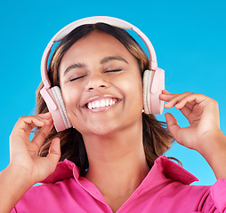 Image showing Headphones, happy music and woman or student with streaming service with mental health podcast in studio. Young african person listening to radio, electronics and audio technology on blue background