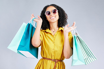 Image showing Portrait, sunglasses and woman smile with shopping bag for fashion in studio isolated on a white background. Cool, sales and African customer with gift, discount deal and stylish clothes from store