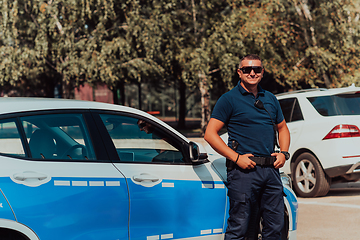 Image showing A policeofficer patrols the city. A police officer with sunglasses patroling in the city with an official police car