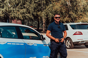 Image showing A policeofficer patrols the city. A police officer with sunglasses patroling in the city with an official police car