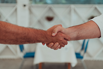 Image showing Close up a handshake, businessman together creates a mutually beneficial business relationship. The economic graph on the table