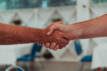 Image showing Close up a handshake, businessman together creates a mutually beneficial business relationship. The economic graph on the table