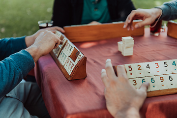 Image showing A group of men drink traditional Turkish tea and play a Turkish game called Okey