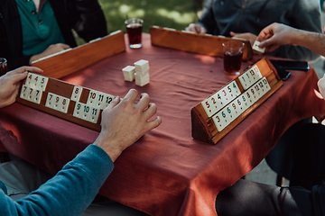 Image showing A group of men drink traditional Turkish tea and play a Turkish game called Okey