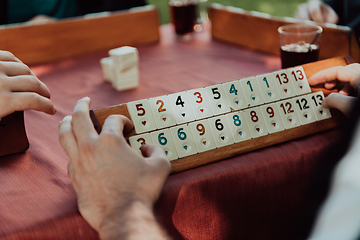 Image showing A group of men drink traditional Turkish tea and play a Turkish game called Okey