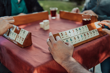 Image showing A group of men drink traditional Turkish tea and play a Turkish game called Okey