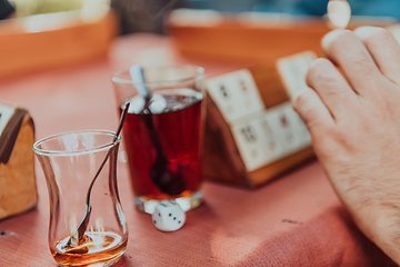 Image showing A group of men drink traditional Turkish tea and play a Turkish game called Okey