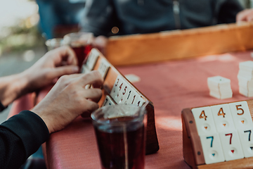 Image showing A group of men drink traditional Turkish tea and play a Turkish game called Okey