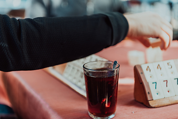 Image showing A group of men drink traditional Turkish tea and play a Turkish game called Okey