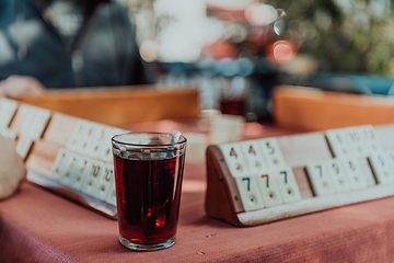 Image showing A group of men drink traditional Turkish tea and play a Turkish game called Okey