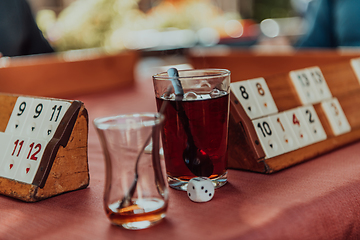 Image showing A group of men drink traditional Turkish tea and play a Turkish game called Okey