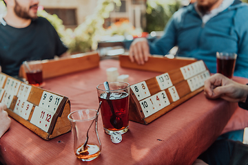 Image showing A group of men drink traditional Turkish tea and play a Turkish game called Okey