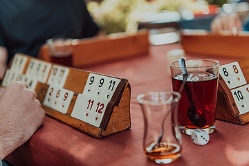 Image showing A group of men drink traditional Turkish tea and play a Turkish game called Okey