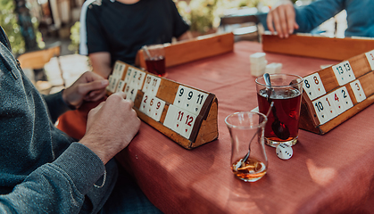 Image showing A group of men drink traditional Turkish tea and play a Turkish game called Okey