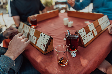 Image showing A group of men drink traditional Turkish tea and play a Turkish game called Okey