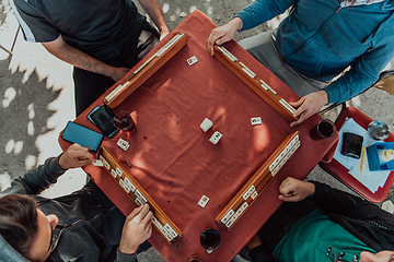 Image showing A group of men drink traditional Turkish tea and play a Turkish game called Okey