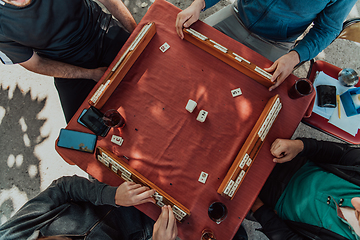 Image showing A group of men drink traditional Turkish tea and play a Turkish game called Okey