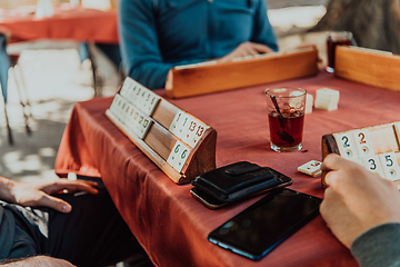 Image showing A group of men drink traditional Turkish tea and play a Turkish game called Okey