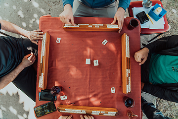 Image showing A group of men drink traditional Turkish tea and play a Turkish game called Okey