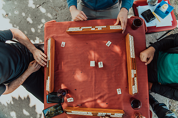 Image showing A group of men drink traditional Turkish tea and play a Turkish game called Okey