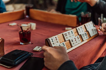 Image showing A group of men drink traditional Turkish tea and play a Turkish game called Okey