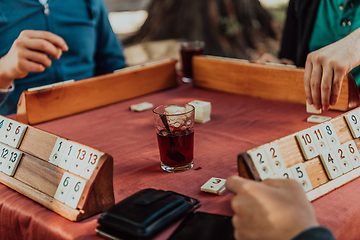 Image showing A group of men drink traditional Turkish tea and play a Turkish game called Okey