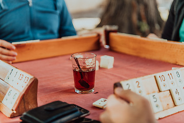 Image showing A group of men drink traditional Turkish tea and play a Turkish game called Okey