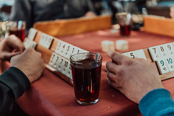 Image showing A group of men drink traditional Turkish tea and play a Turkish game called Okey