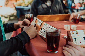 Image showing A group of men drink traditional Turkish tea and play a Turkish game called Okey