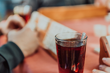 Image showing A group of men drink traditional Turkish tea and play a Turkish game called Okey