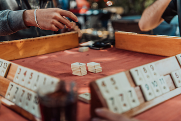 Image showing A group of men drink traditional Turkish tea and play a Turkish game called Okey