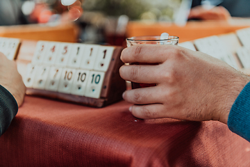 Image showing A group of men drink traditional Turkish tea and play a Turkish game called Okey