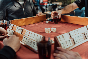 Image showing A group of men drink traditional Turkish tea and play a Turkish game called Okey