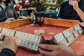 Image showing A group of men drink traditional Turkish tea and play a Turkish game called Okey