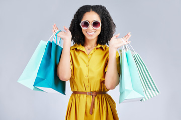 Image showing Sunglasses, portrait and happy woman with shopping bag for fashion in studio isolated on a white background. Cool, sales and African customer with gift, discount deal and stylish clothes from store