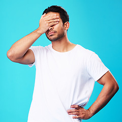 Image showing Man, face palm and mistake in studio with thinking, regret and anxiety for fail by blue background. Young guy, student and cover eyes with stress, memory and shame for bad decision with depression