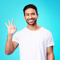 Image showing Happy, perfect gesture and portrait of a man in a studio with an agreement sign or expression. Happiness, smile and young Indian male model with an approval hand emoji isolated by a blue background.