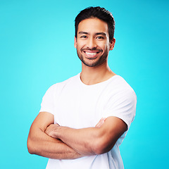 Image showing Smile, happy and portrait of Asian man arms crossed with casual fashion isolated in a studio blue background. Relax, calm and young male person proud or confident mindset, natural and happiness