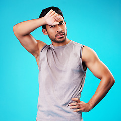 Image showing Portrait, fitness and Asian man tired after exercise in studio isolated on a blue background. Face, serious and athlete with fatigue, wipe sweat and workout for sports, healthy body and wellness