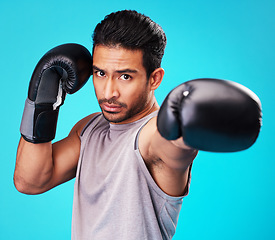 Image showing Portrait, man and training with boxing, punch and sports .challenge against a blue studio background. Male person, competition and serious boxer with power, strong or energy with exercise or fighting