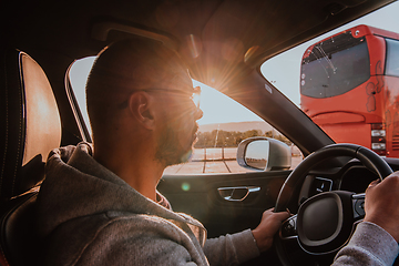 Image showing A man with a sunglasses driving a car at sunset. The concept of car travel