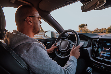 Image showing A man with a sunglasses driving a car at sunset. The concept of car travel