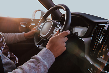 Image showing Close up man hand driving a car at sunset. The concept of car travel