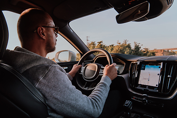 Image showing A man with a sunglasses driving a car at sunset. The concept of car travel