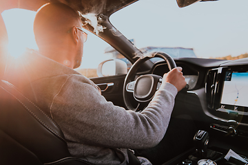 Image showing A man with a sunglasses driving a car at sunset. The concept of car travel