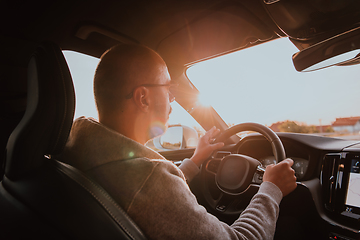 Image showing A man with a sunglasses driving a car at sunset. The concept of car travel