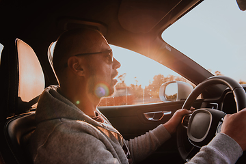 Image showing A man with a sunglasses driving a car at sunset. The concept of car travel